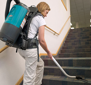 le personnel d’entretien utilisant un aspirateur dorsal de Tennant pour nettoyer les escaliers recouverts de tapis d’un immeuble de bureaux le personnel d’entretien utilisant un aspirateur dorsal de Tennant pour nettoyer les escaliers recouverts de tapis d’un immeuble de bureaux